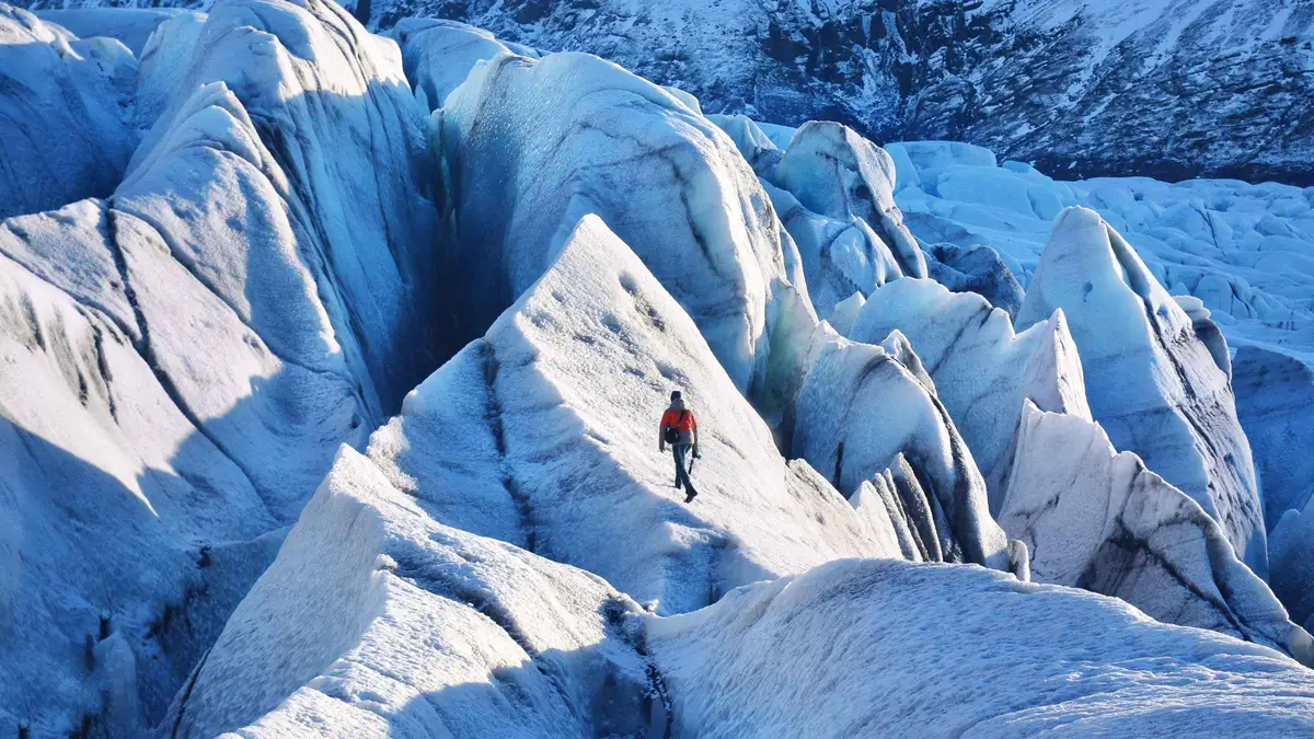 A guided group in crampons walking sparkling blue ice on a beginner Skaftafell glacier hike in Vatnajökull National Park, Iceland